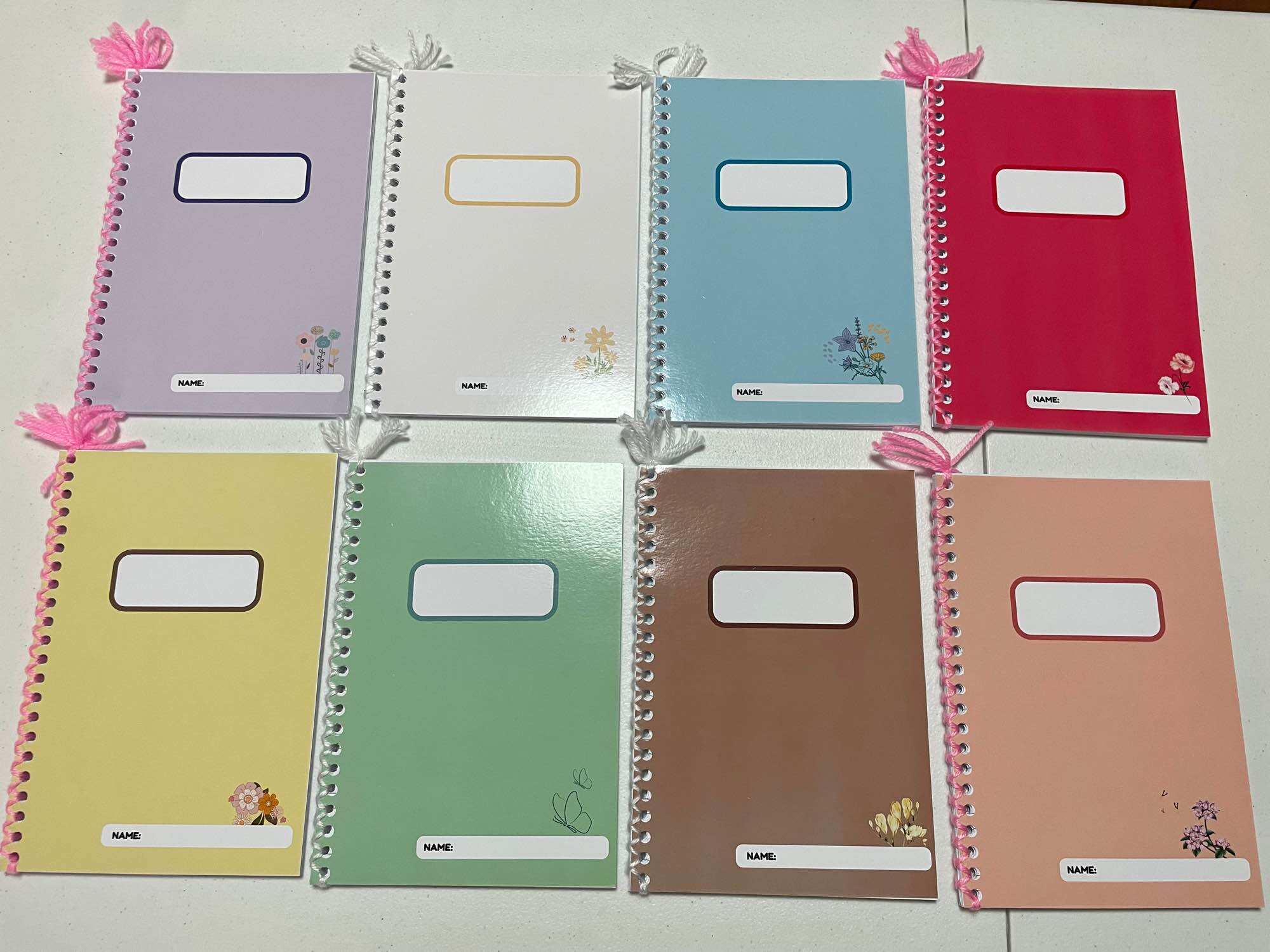 Set of 8 color coded A5 writing notebooks for grade school and high school students with floral designs and label slots. Flower minimalist design with free pen